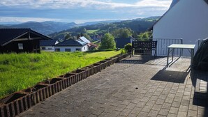 A paved pathway leading to a building with a white exterior, a bench, and a table. - Vacation apartment on the Nordschleife (Wimbach)