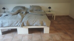 A bedroom with a bed, two bedside tables, and a tiled floor. - Vacation apartment on the Nordschleife (Wimbach)