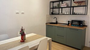 A compact kitchen with a sink, microwave, and shelves above the counter.