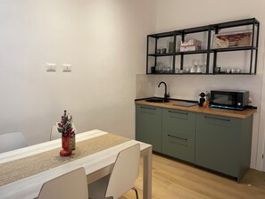 Cocina pequeña con fregadero, microondas y estantes sobre la encimera.