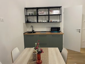 Een moderne keuken met een magnetron, spoelbak en open planken.