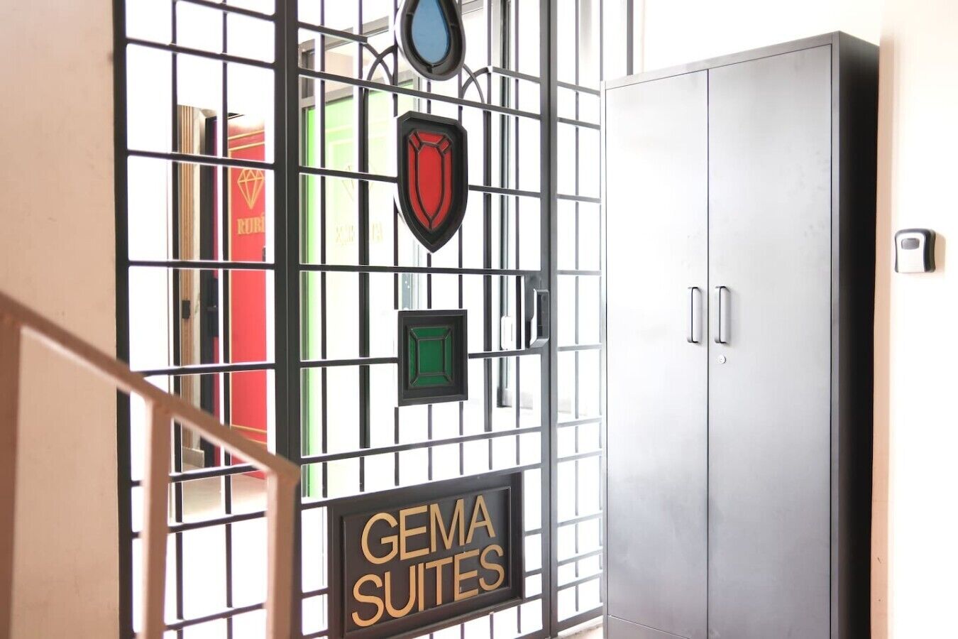 Une porte métallique surmontée d’une enseigne indiquant « GEMA SUITES » et dotée d’une poignée.