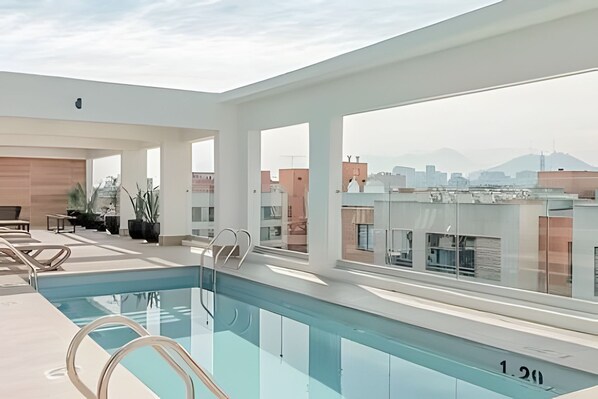 A rooftop pool with clear views of the cityscape, including buildings and mountains.
