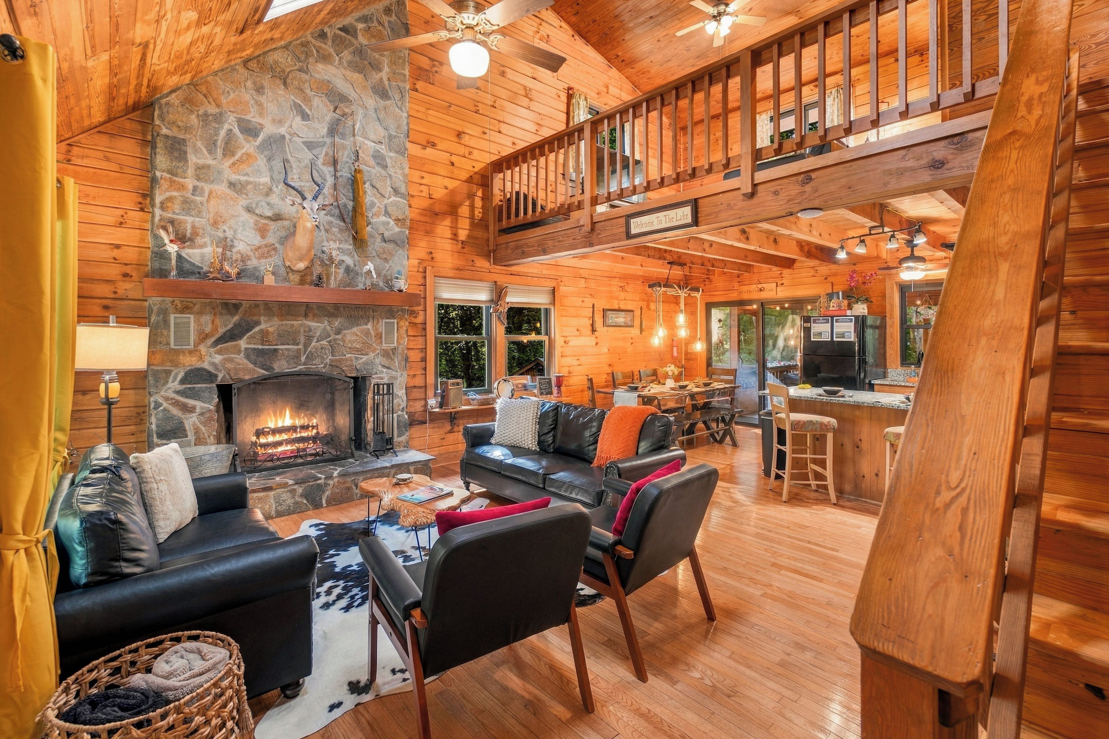 A spacious lodge with a stone fireplace, leather seating, and a dining area.