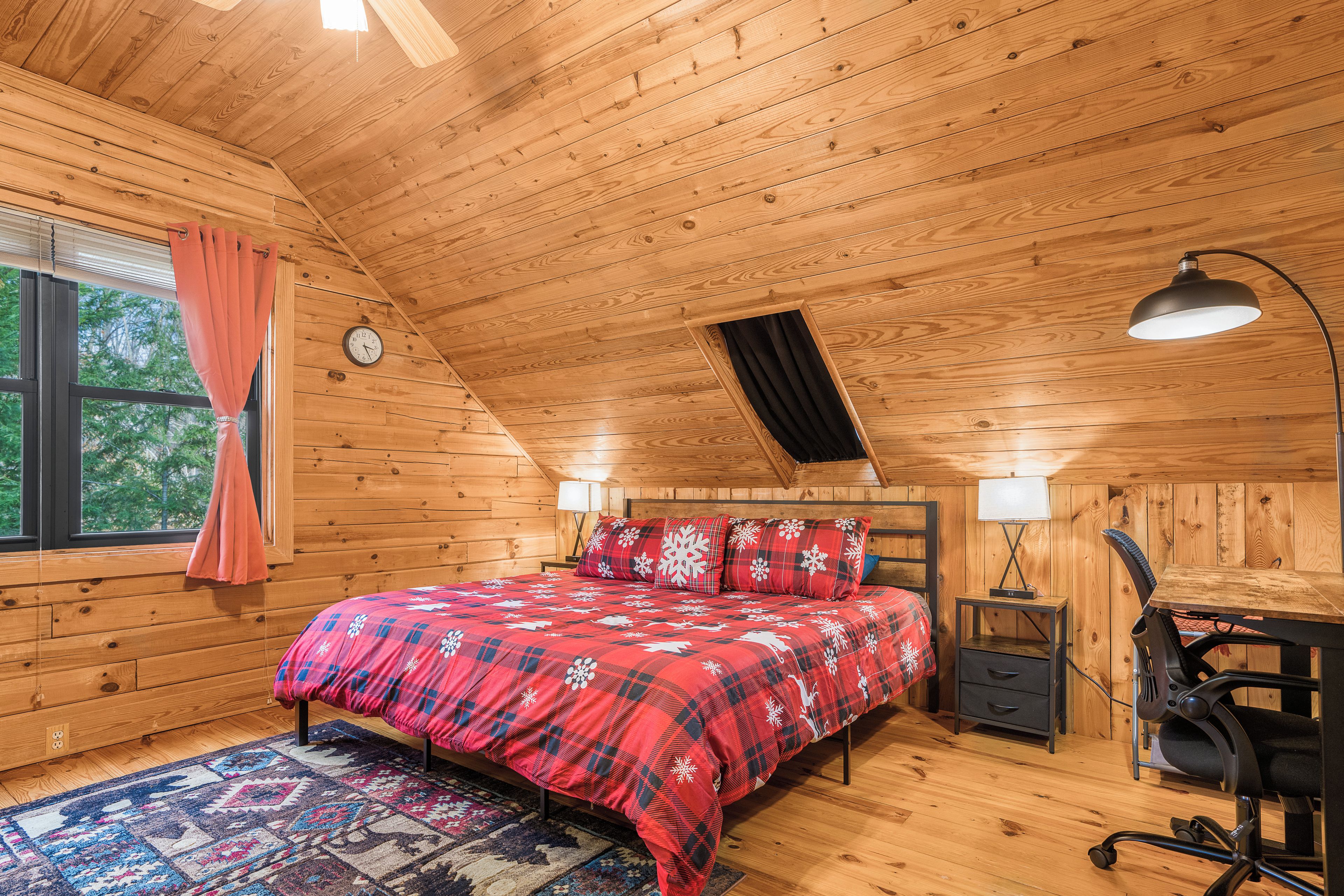 Un dormitorio de cabaña de madera acogedor, con cama, lámparas de noche, un escritorio y una silla.