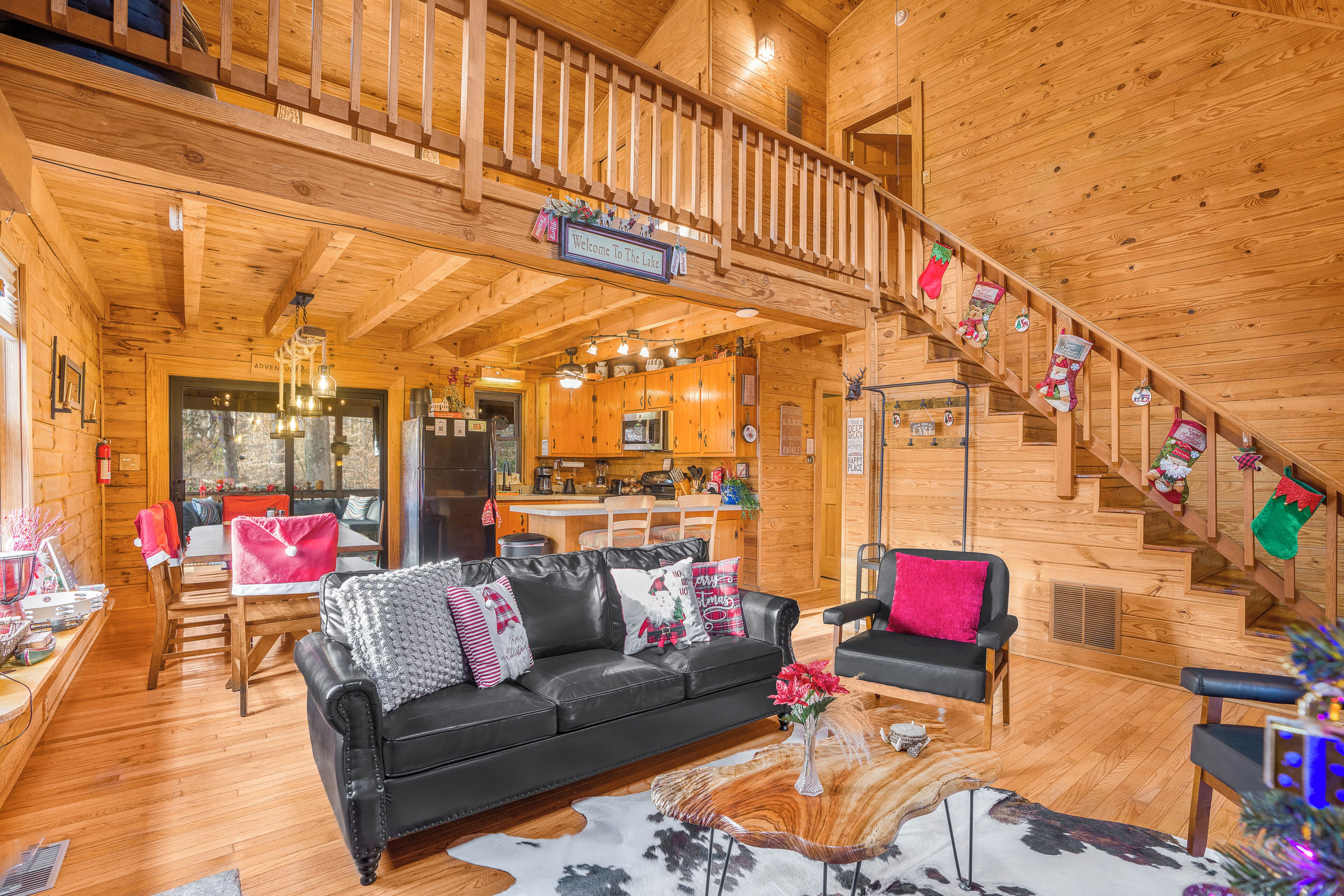 Ein Interieur einer Holzhütte mit einem schwarzen Ledersofa, einer Essecke, einer Küche und einer Treppe.