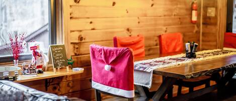 A cozy cabin-style interior with a wooden wall, a dining table with a placemat, and a bench with a pink towel.
