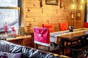 Interior acollidor d'estil cabana, amb una paret de fusta, taula de dinar amb motlle i una banca amb tovallola rosa.