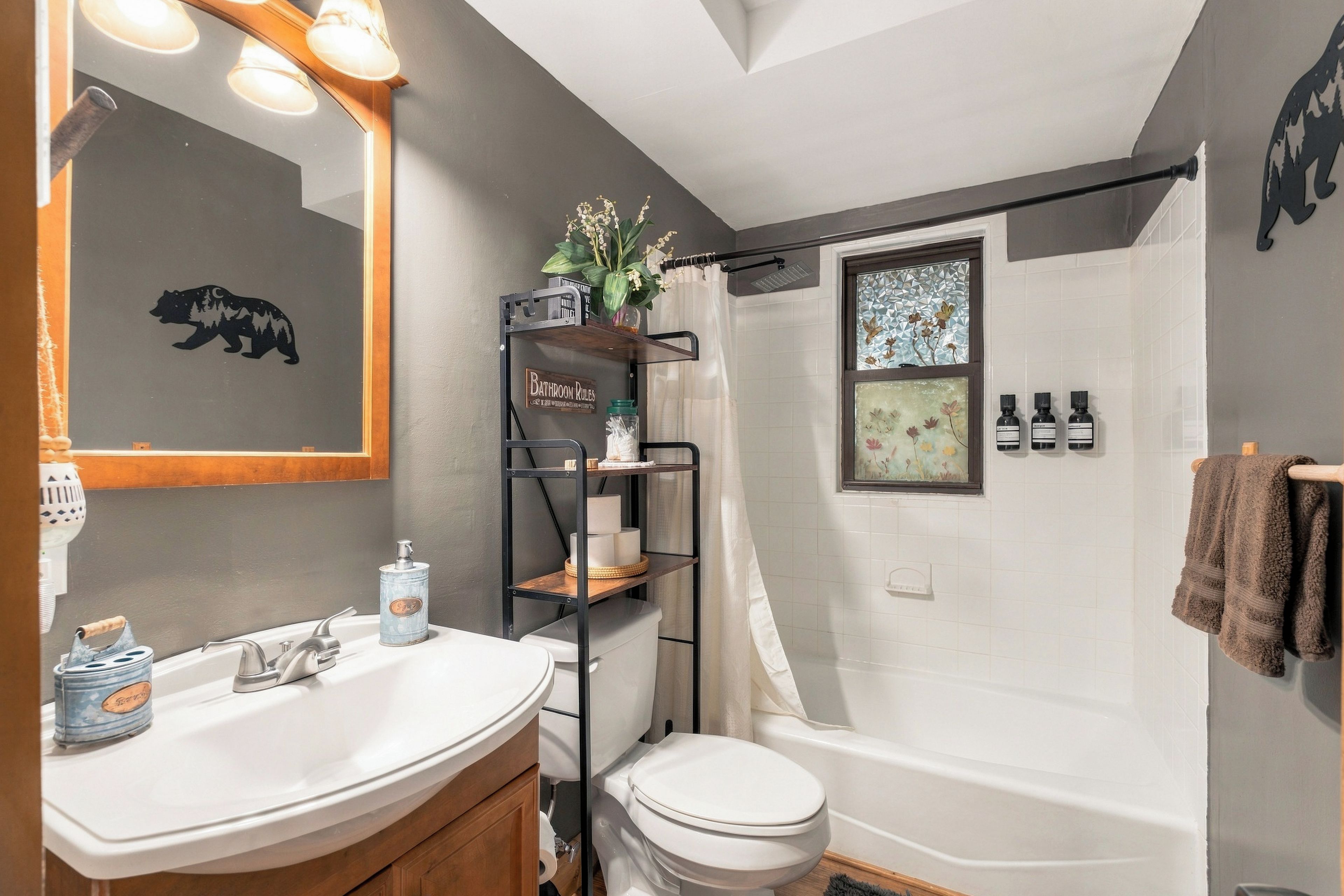 A bathroom with a white sink, toilet, and bathtub. There is a shelf with toiletries and a shower curtain.