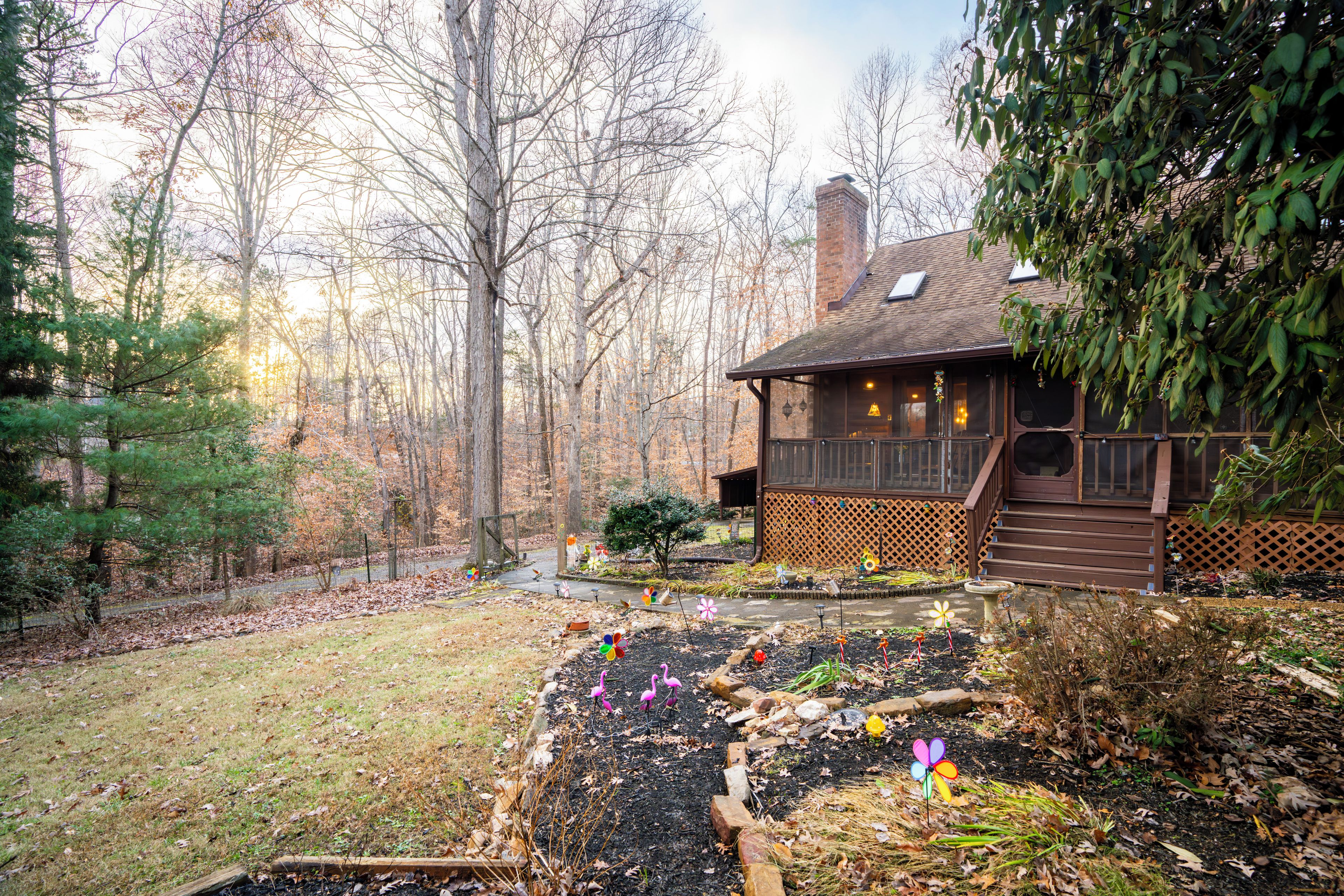 A wooden cabin with a deck, surrounded by a forested area with leafless trees.