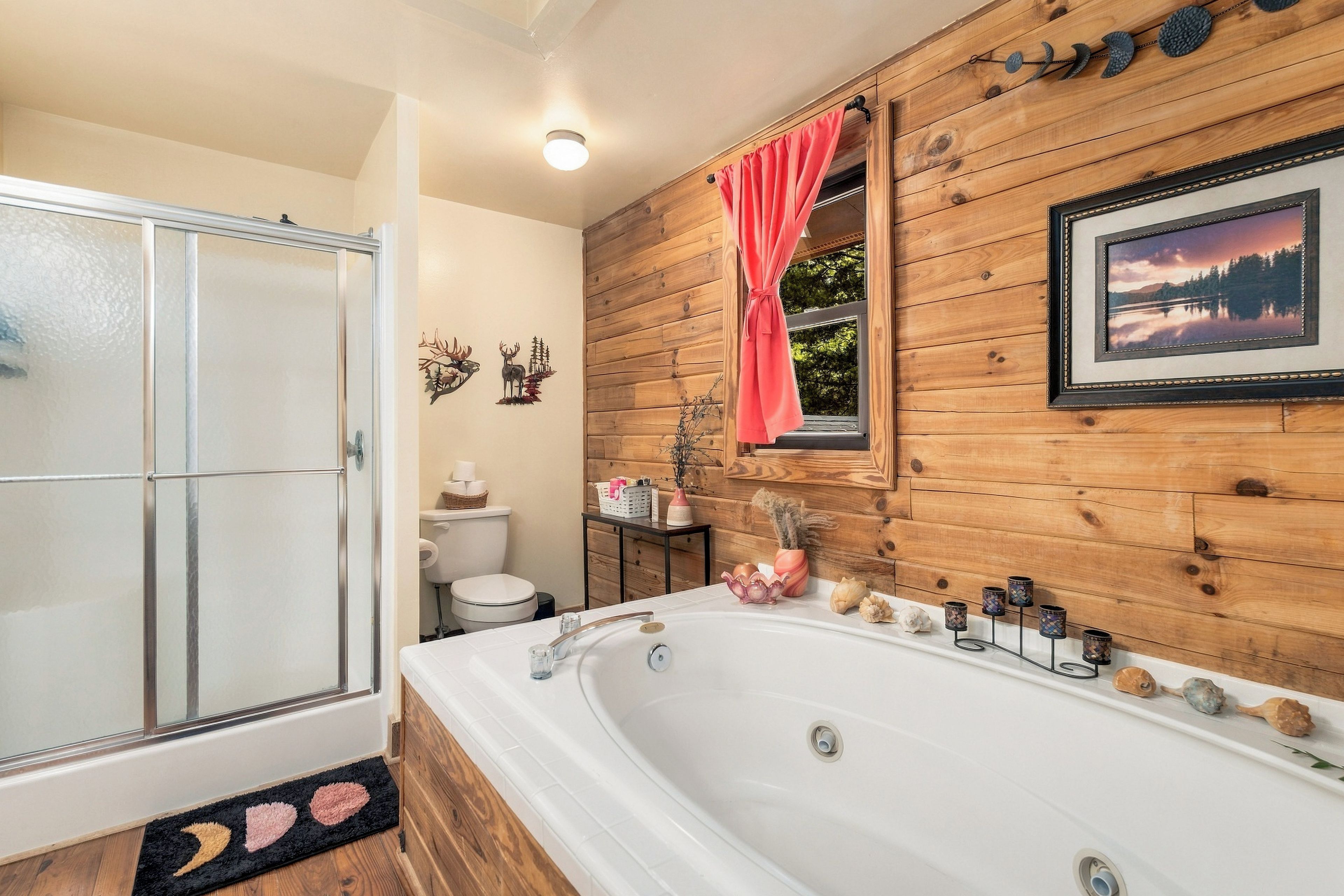 A bathroom with a wooden wall, a bathtub, a shower, and a window with a curtain.