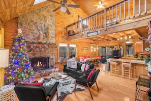 A spacious living area with a fireplace, a Christmas tree, and a cozy seating arrangement.