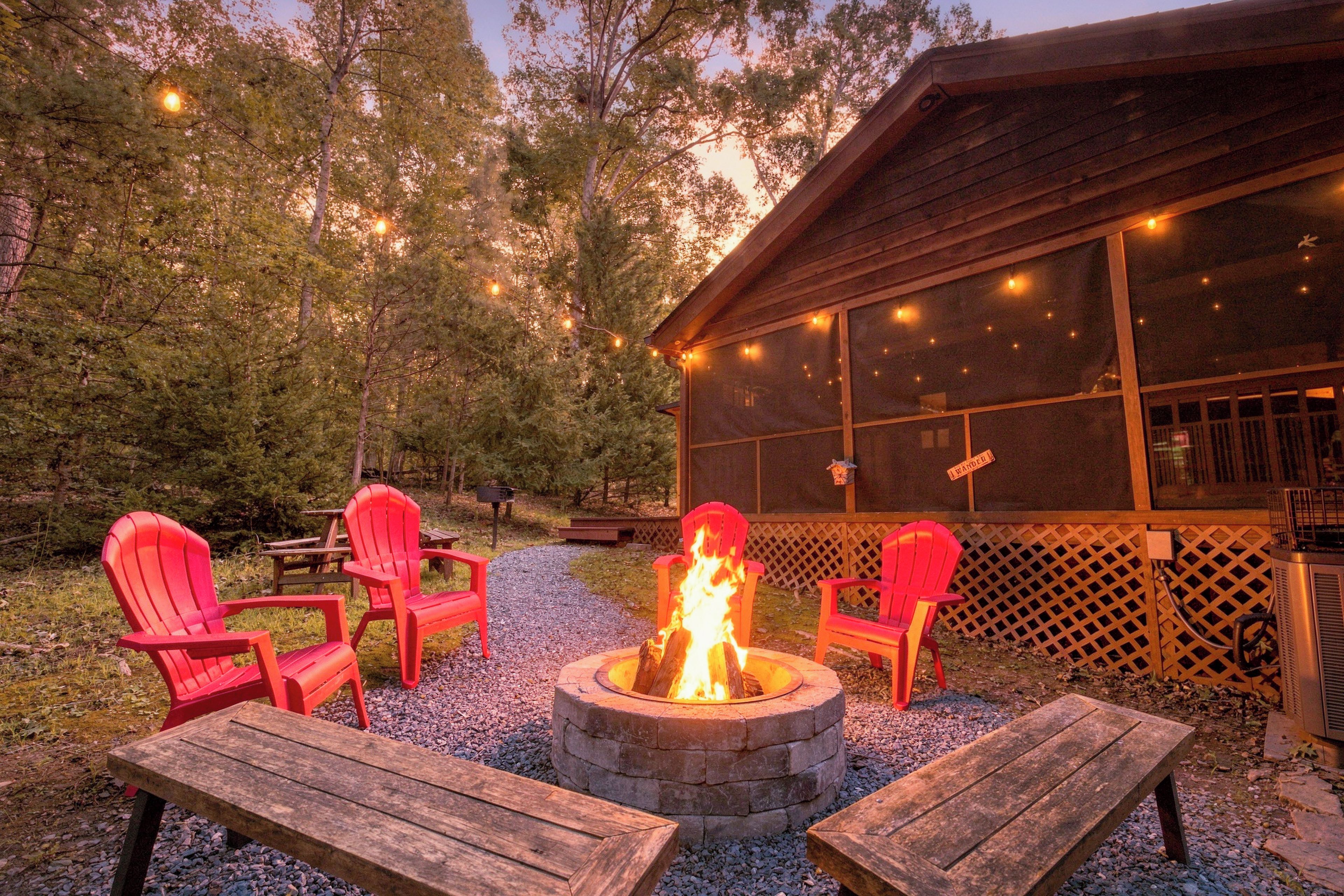 Eine Holzhütte mit Feuerstelle, umgeben von roten Adirondack-Stühlen und Holzbanken.