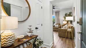 A modern living room with a wooden floor, a round mirror, a lamp, a small table with decorative items, and a sofa. - RiverStone Resort • Upscale 1BR•1BA Condo · Sleeps 4• Lazy River•Pool•Hot Tubs (Pigeon Forge)