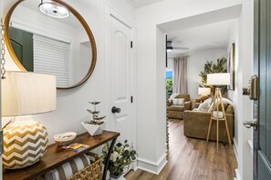 A modern living room with a wooden floor, a round mirror, a lamp, a small table with decorative items, and a sofa. - RiverStone Resort • Upscale 1BR•1BA Condo · Sleeps 4• Lazy River•Pool•Hot Tubs (Pigeon Forge)