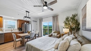 A modern bedroom with a large bed, a desk, and a balcony with a view. - RiverStone Resort • Upscale 1BR•1BA Condo · Sleeps 4• Lazy River•Pool•Hot Tubs (Pigeon Forge)