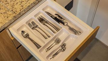 A drawer with neatly arranged cutlery including forks, knives, spoons, and a bottle opener.