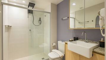 A bathroom with a glass-enclosed shower, a toilet, a sink, and a mirror above the sink.
