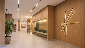 A modern hotel lobby with a reception desk, seating area, and a large wall art piece. - Stay Home João Cachoeira - Piscina - Gym (São Paulo)
