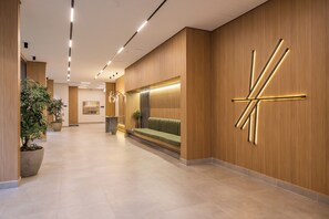 Un hall d’hôtel moderne comprenant un comptoir d’accueil, un espace salon et une grande œuvre d’art murale.