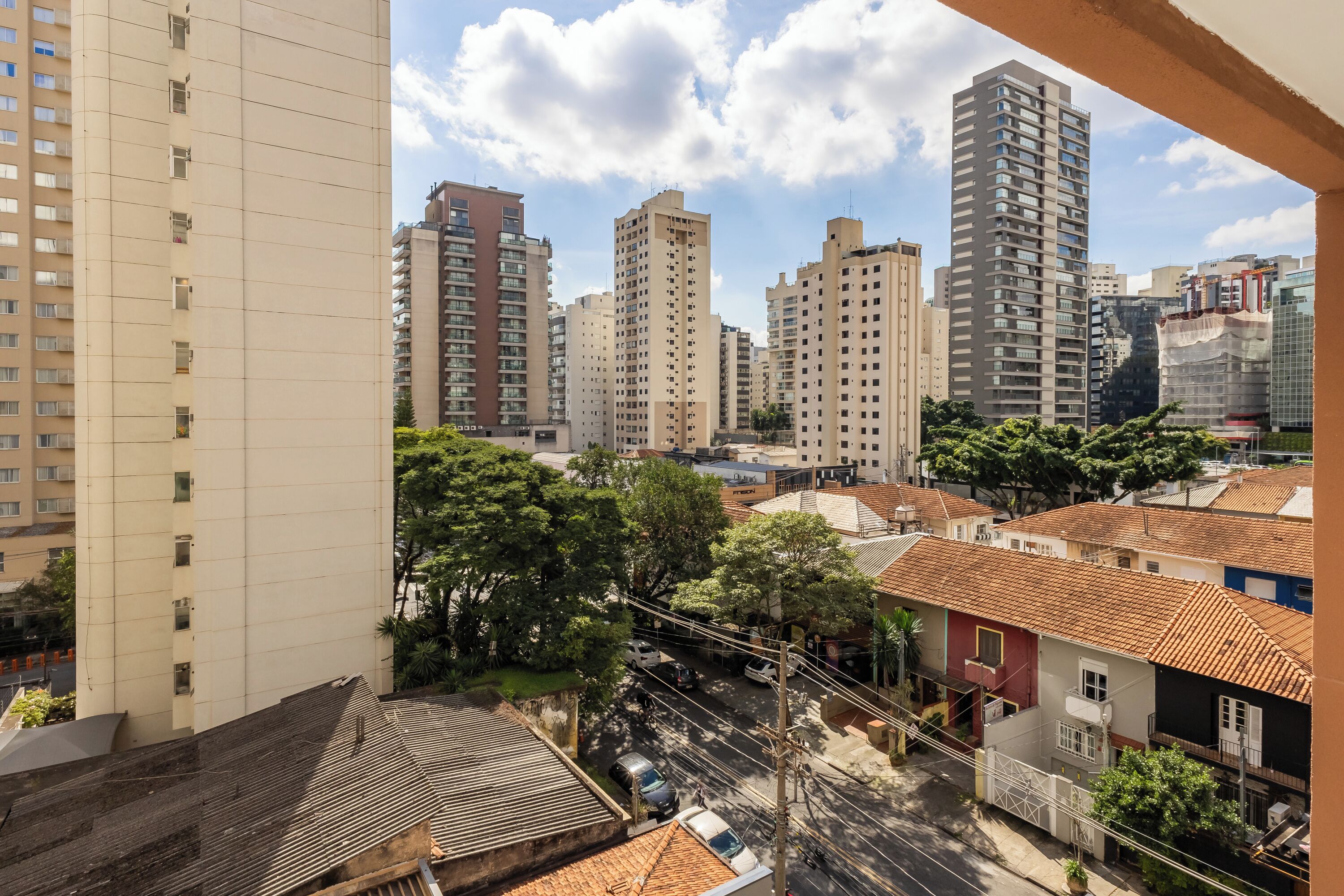 A high-rise building with multiple floors, a street with cars, and surrounding residential buildings.