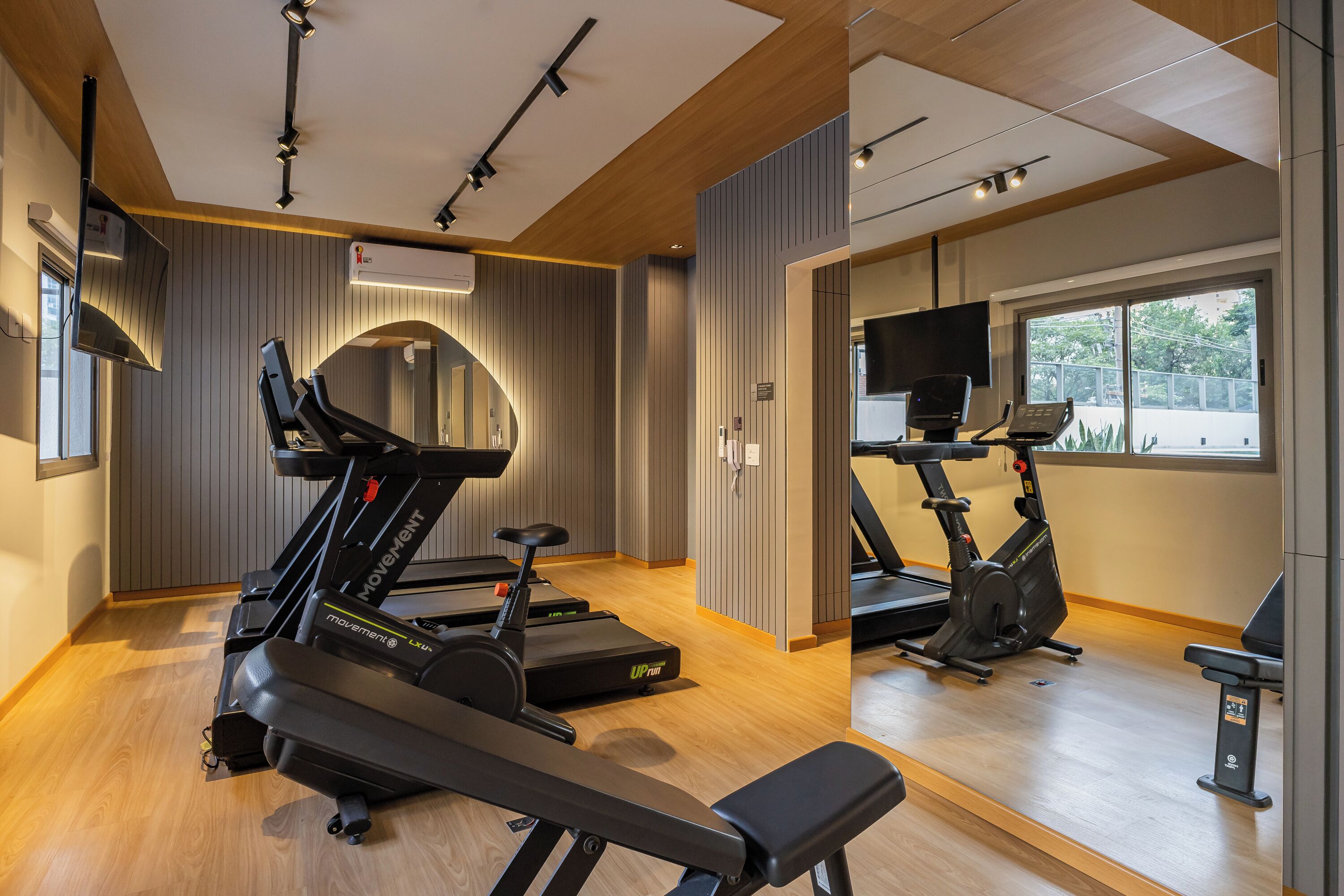 Une salle de sport équipée de tapis de course, d’un vélo d’appartement et d’un banc de musculation.