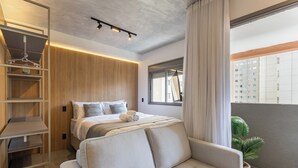 A modern bedroom with a bed, a sofa, a built-in wardrobe, and a potted plant. - Stay Home João Cachoeira - Piscina - Gym (São Paulo)