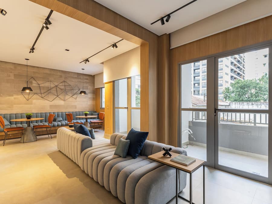 Uma sala de estar moderna com um sofá, cadeiras, uma mesa e uma janela grande com vista para edifícios e árvores.