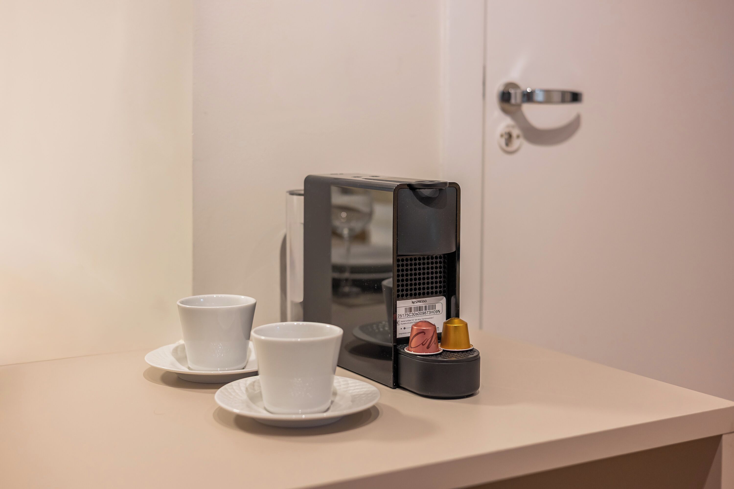 A coffee machine with a cup and saucer, a small container with a can and a bottle, and a door with a handle.