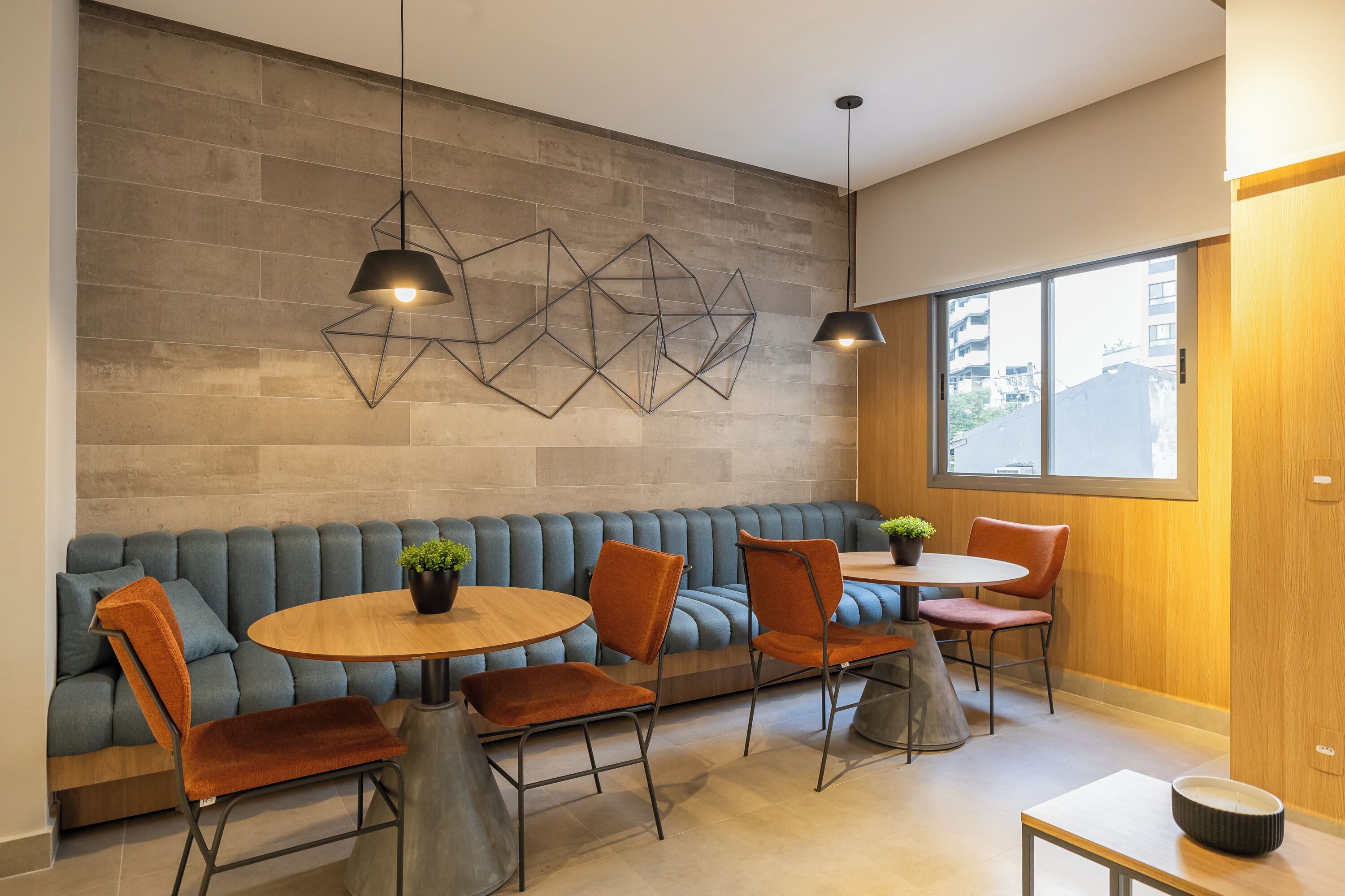 Un interior moderno con un sofá, sillas, una mesa redonda e iluminación colgante.