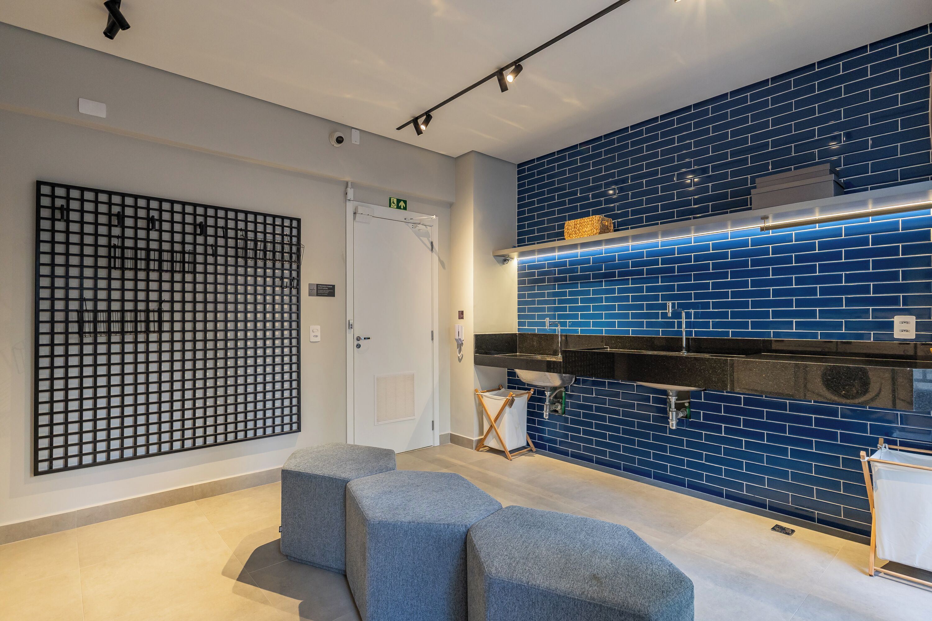 A modern hotel lobby with a blue-tiled wall, a black grid-patterned wall, and a white door.