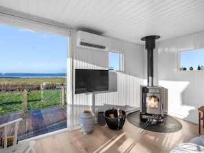Ein modernes Wohnzimmer mit Kamin, Flachbildfernseher und Meerblick.