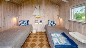 Een kamer met twee bedden, een houten plafond, een raam en een hangende zeil.