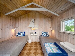 Ein Zimmer mit zwei Betten, einer Holzbalkendecke, einem Fenster und einer hängenden Segeltuch.