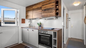 Een moderne keuken met houten kastjes, een ingebouwde oven en een raam met uitzicht.