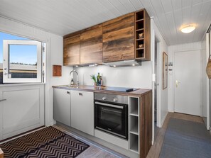 Eine moderne Küche mit Holzausstattung, einem eingebauten Backofen und einem Fenster mit Blick.