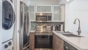 A modern kitchen with stainless steel appliances, a dishwasher, and a built-in oven. - ⚽ FIFA World Cup 2026 | Furnished Coal Harbour Condo | Parking Included (Vancouver)
