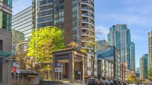 A tall, curved building with multiple floors and balconies, surrounded by other high-rise buildings. - ⚽ FIFA World Cup 2026 | Furnished Coal Harbour Condo | Parking Included (Vancouver)