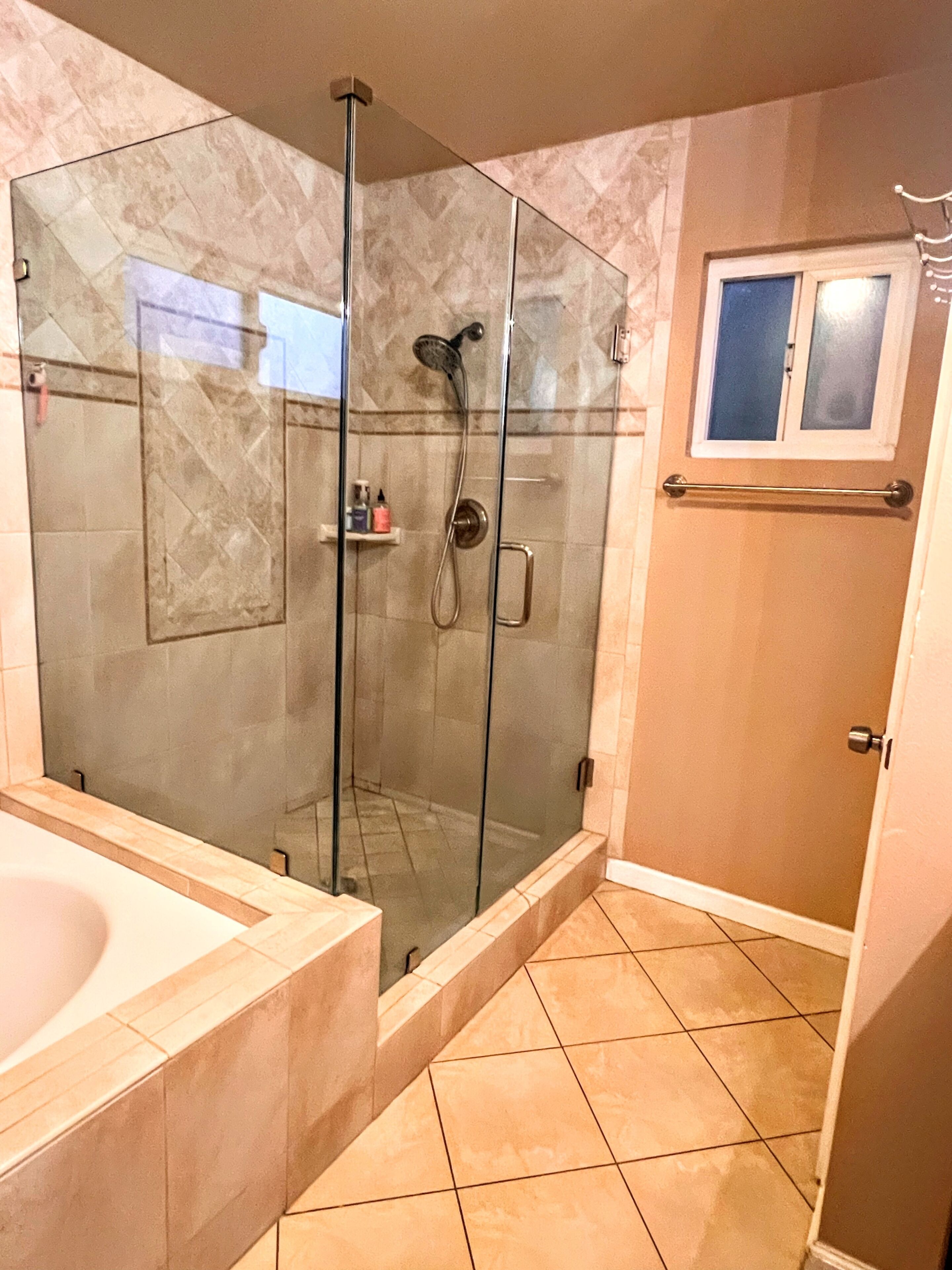 A modern bathroom with a glass-enclosed shower, a bathtub, and a toilet.