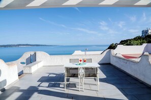 Une terrasse avec une table et des chaises, offrant une vue sur la côte.