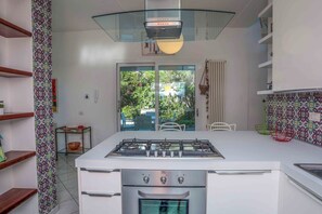 Una cuina moderna amb una illa central, forn de foc i vitroceràmica.