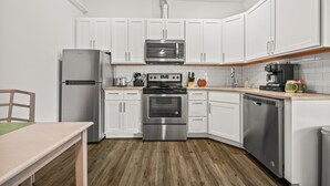 Een moderne keuken met witte kasten, roestvrijstalen apparatuur en een houten vloer.