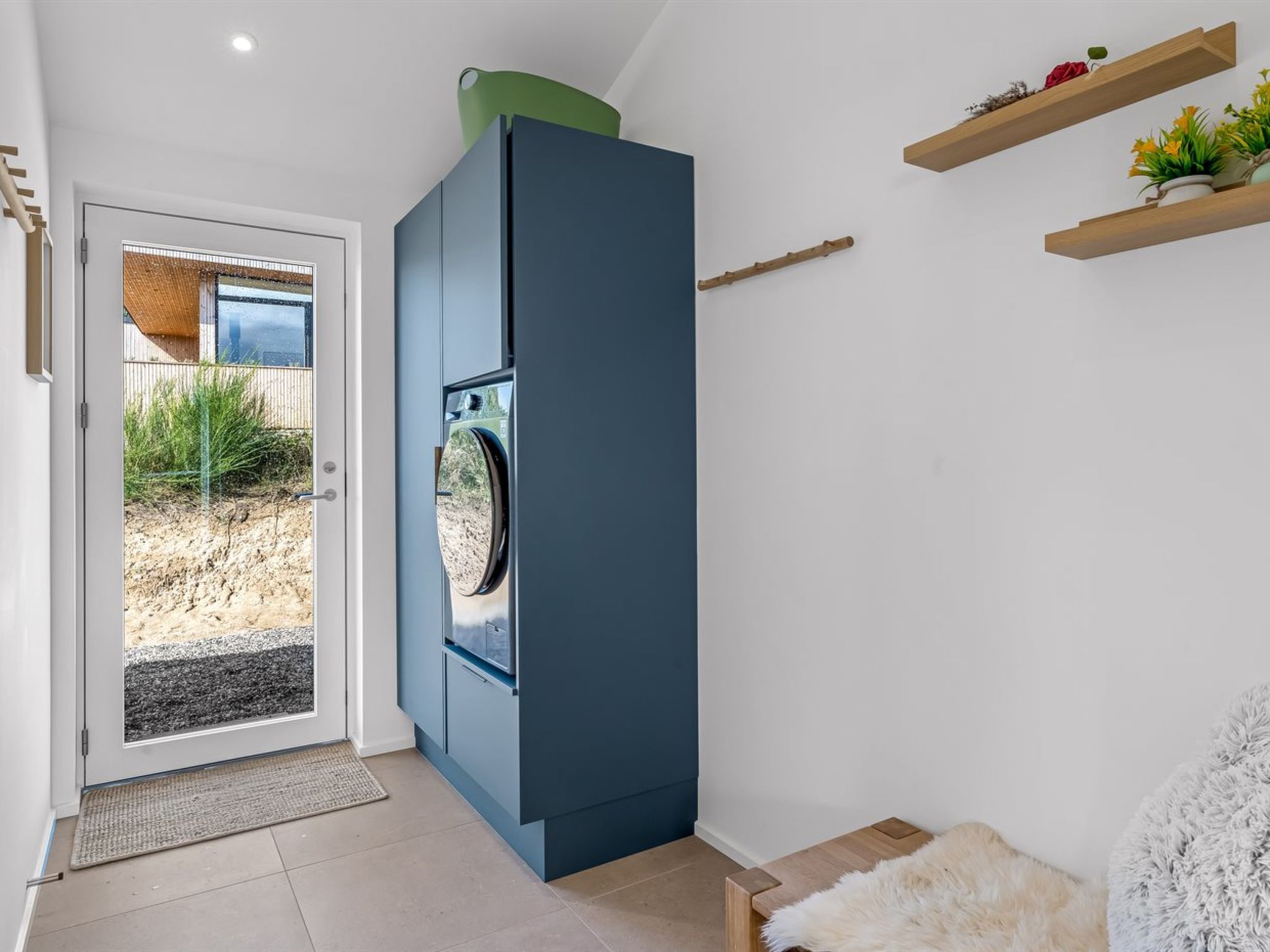A compact living space with a built-in washer and dryer, a door leading to an outdoor area, and a small seating area with a furry rug.
