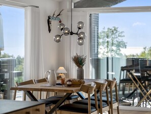 A dining area with a table set for four, a pitcher, a vase with dried plants, and a sign on the wall. - "Theodora" - 600m from the sea by Interhome (Knebel)
