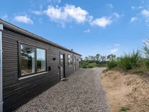 Un bâtiment moderne avec une allée en gravier et une zone sablonneuse à côté.