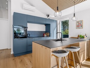 Une cuisine moderne avec des meubles bleus, un îlot central en bois et des tabourets de bar.