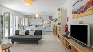 A modern living room with a sofa, television, and a kitchen in the background. - La Soberana: The House That Cares for You (Arroyo)
