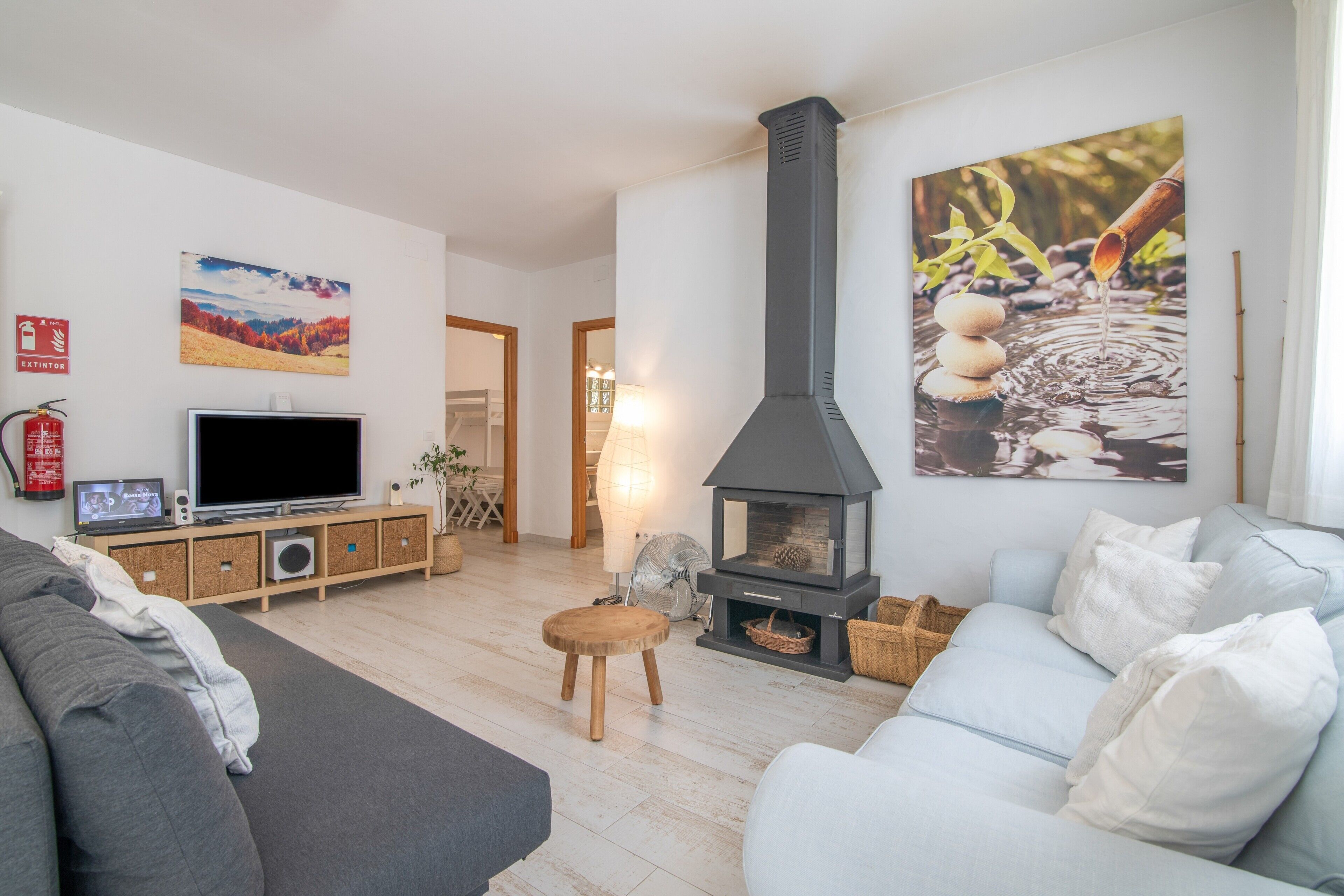 Una sala de estar con chimenea, televisión, sofá y obras de arte en las paredes.