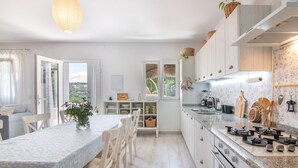 A modern kitchen with white cabinets, a granite countertop, and a dining area with a table and chairs. - La Soberana: The House That Cares for You (Arroyo)