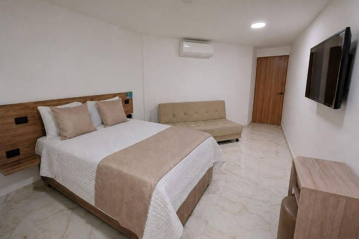 A bedroom with a bed, a sofa, a TV, and a wooden cabinet.